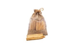 De afbeelding toont Palo Santo stokjes verpakt in een doorzichtig gedeelte van een jute zakje, dichtgebonden met een jute touwtje. De houten stokjes zijn lichtgeel met gladde, rechte randen, kenmerkend voor Palo Santo hout, dat vaak gebruikt wordt om zijn aromatische en spirituele eigenschappen. De eenvoud van de verpakking benadrukt het natuurlijke en organische karakter van het product.