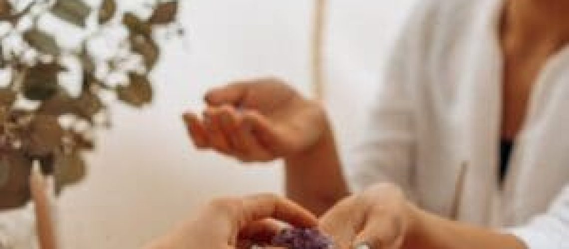 Twee mensen wisselen een edelsteen uit in een rustige setting, die de opkomst van De spirituele winkel en zijn serene, inspirerende sfeer weerspiegelt.